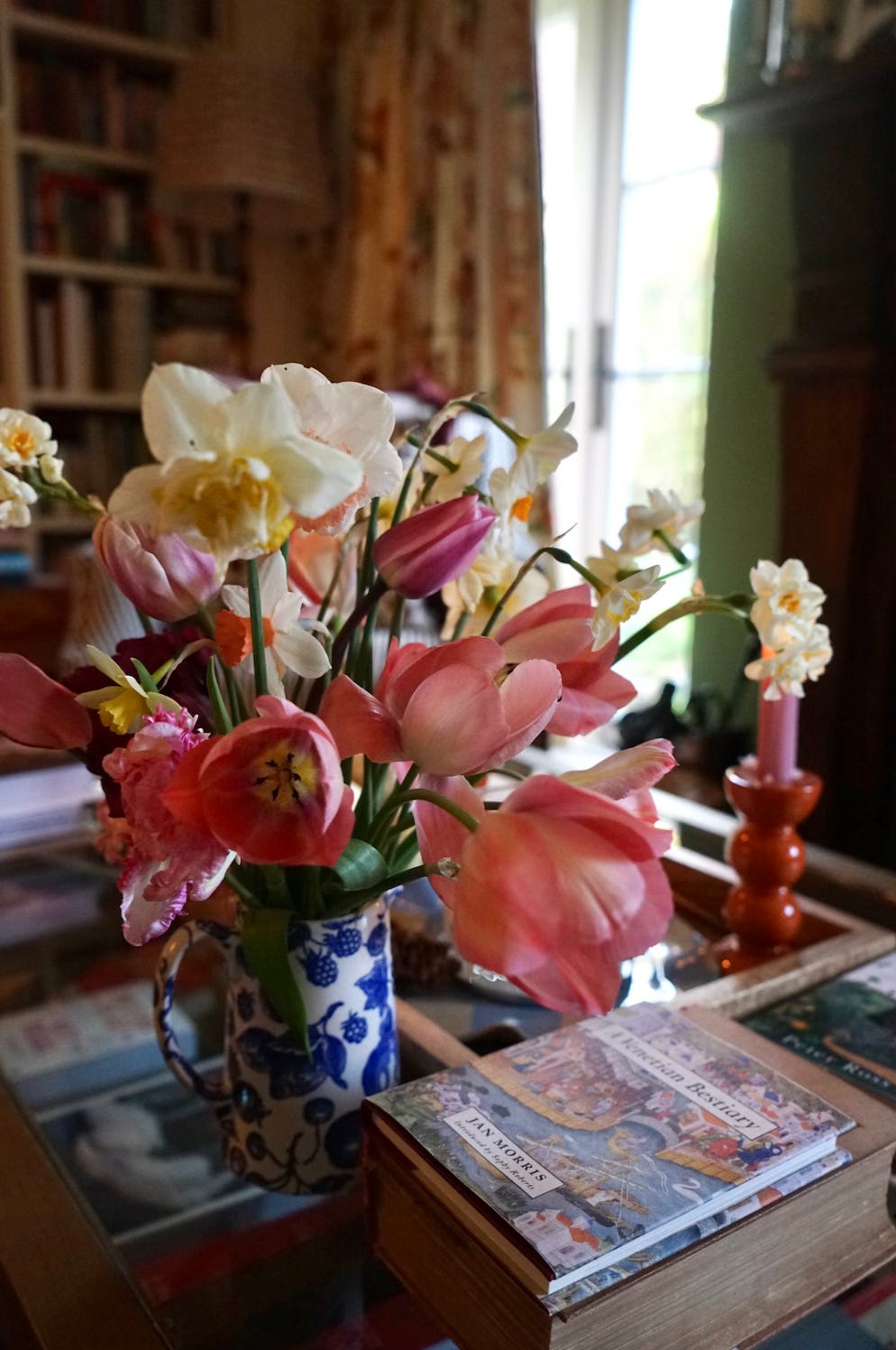Spring bouquet of pink tulips and white daffodils in a blue and white jug on a table indoors