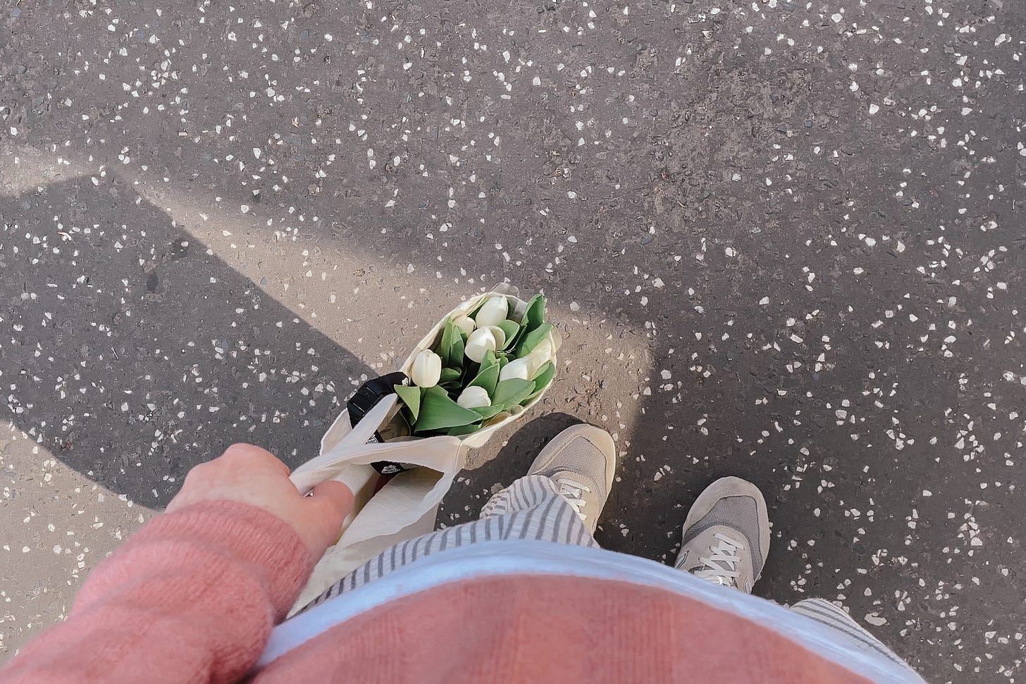 View from above of my pink jumper, striped trousers, grey trainers, and a tote bag with fresh white tulips poking out.