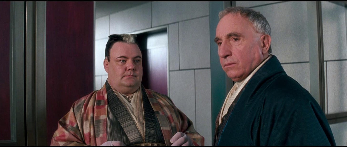 As characters from Demolition Man, Associate Bob is a white streaked grovelling imp of a man, and his boss Cocteau is a white supremacist dressed like he just stepped out of feudal Japan