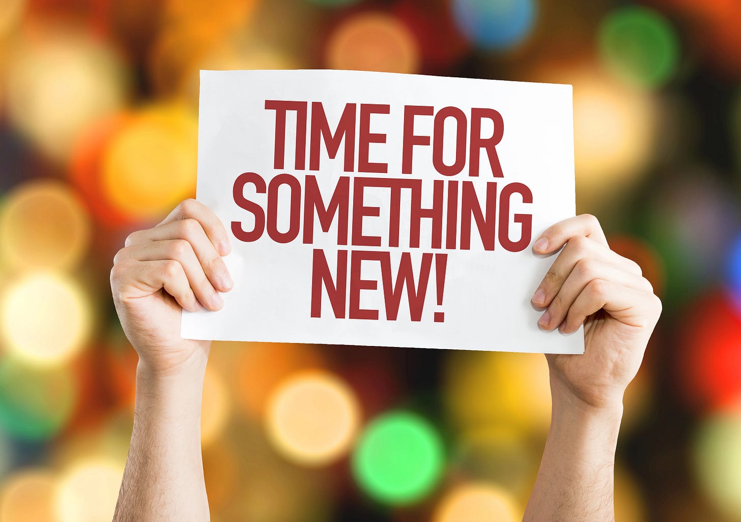 Hands holding a sign that says "Time for something new"