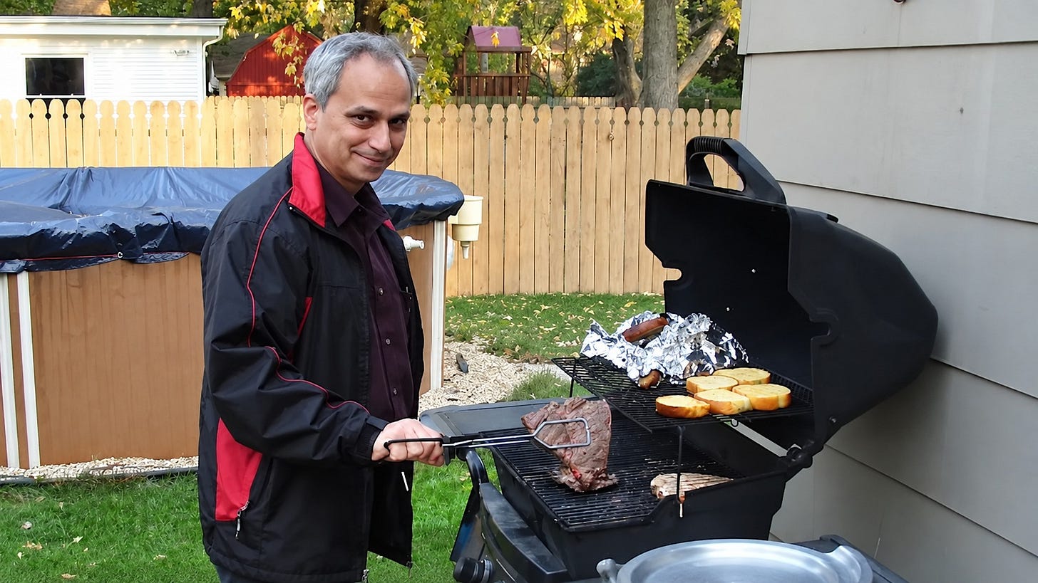 Robert Prevost standing at a charcoal grill in a backyard Robert Prevost standing at a charcoal grill in a backyard
