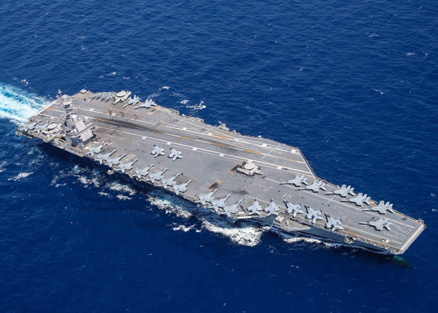 A aircraft carrier with jets on the deck

AI-generated content may be incorrect.