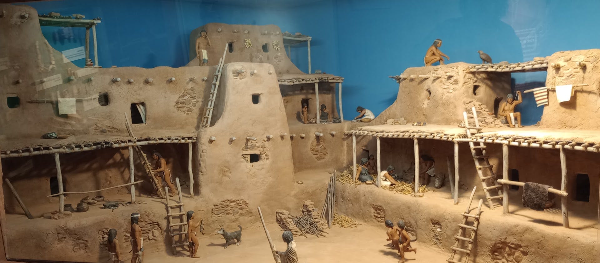 Diorama showing people working, building, and playing in Pecos