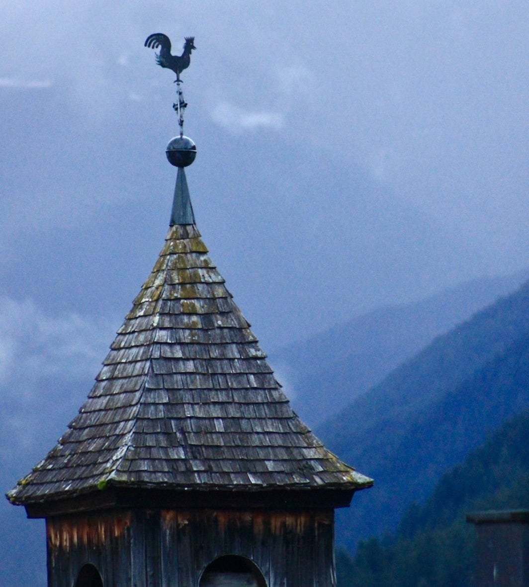 A clock tower with a weather vane on top of it