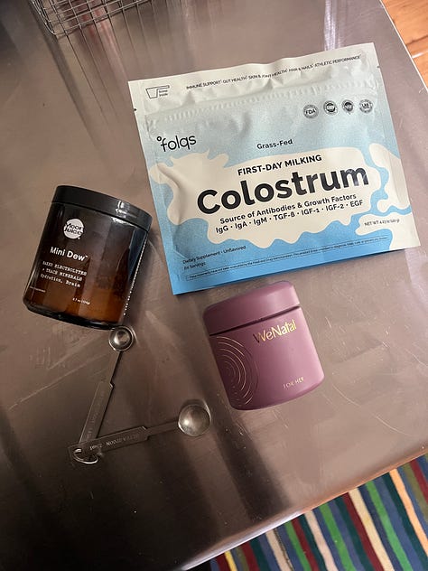 A hand holding a hand sanitizer spray bottle; a green glossy box tissue cover; a flat lay of supplements; a to-go cup of soup; the book cover for Nicotine by Nell Zink; linen striped sheets