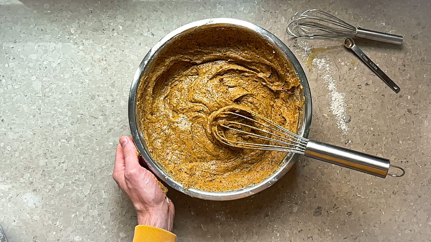 A mixing bowl and whisk filled with pumpkin bread batter.