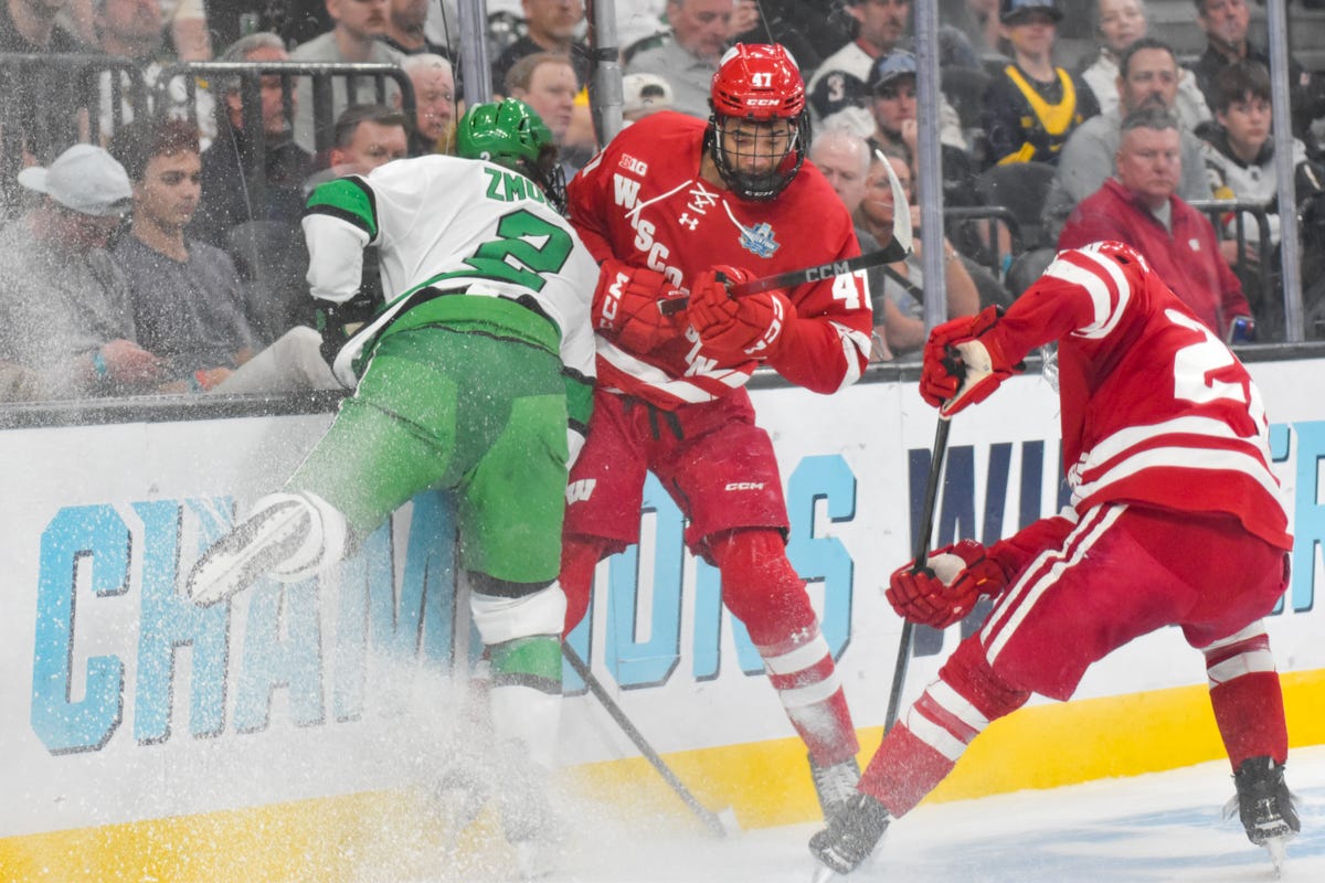 Zmolek hits the boards with two Wisconsin players near them