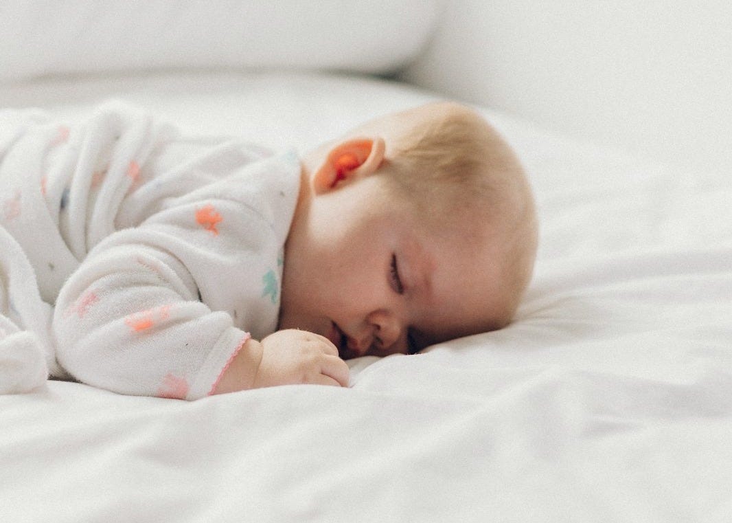 photo of baby laying on bed