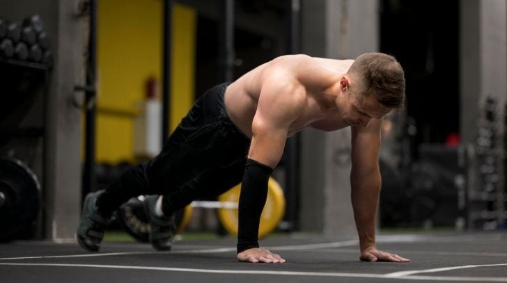 Man performing a burpee push-up in a gym setting Man performing a burpee push-up in a gym setting