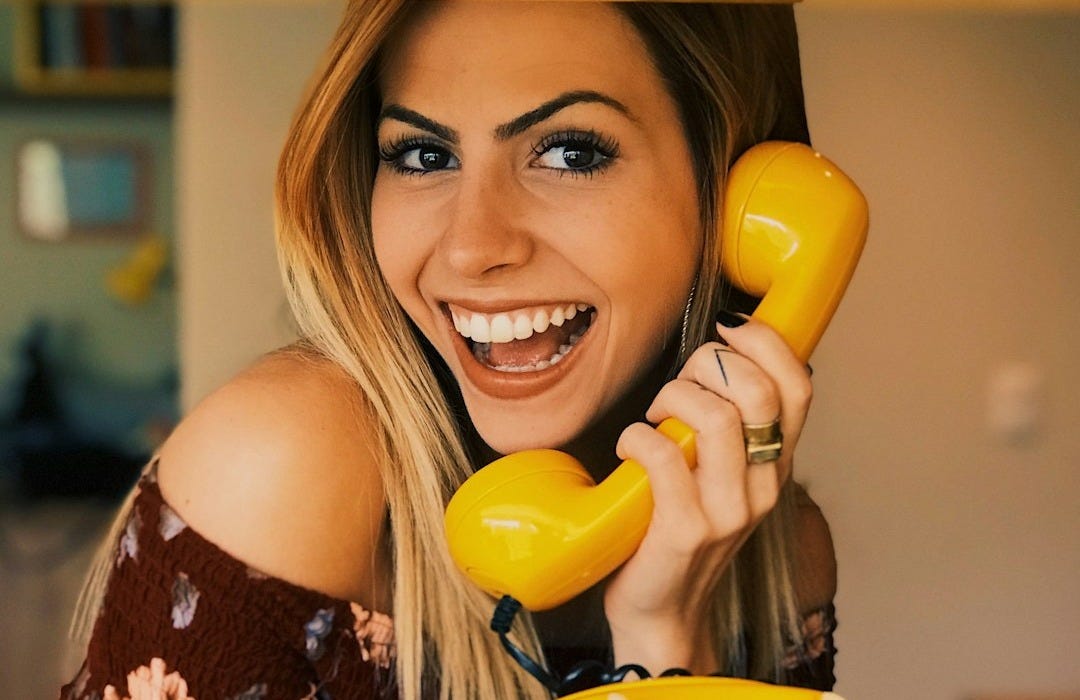 woman holding yellow rotary telephone