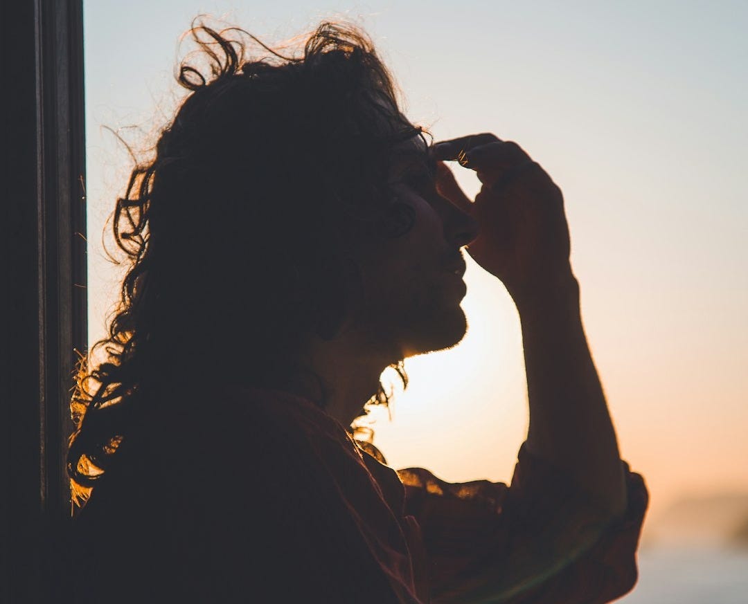 man holding forehead under sunset man holding forehead under sunset