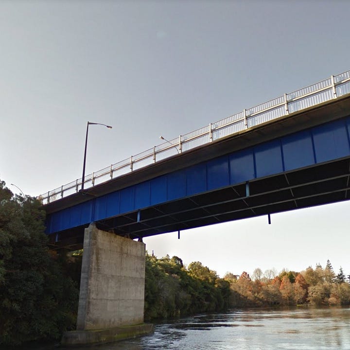 Left: A view from the river, looking up to the bridge - it's painted blue and has a white handrail on the footpath. There is one leg of the bridge going into the river itself. Right: An aerial view of the bridge, in black and white, with lots of people standing on the footpath and traffic on the bridge. There is still scaffolding under the bridge.