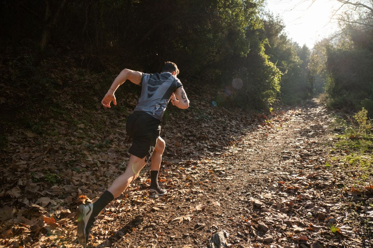 Person sprinting on a leafy trail.