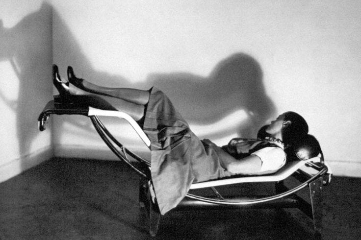 This may contain: a man laying on top of a chair next to a wall