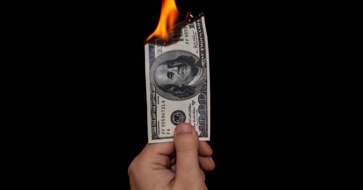 human hand with a 1000 dollar bill being burned
