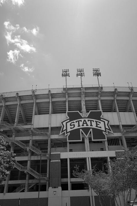 Mississippi State football stadium, campus with American flag, cowbell