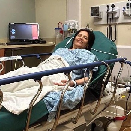 Anu lies in a hospital bed receiving treatment