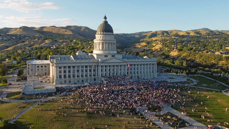 A large crowd of protesters gathers in front of a state capitol building. A large crowd of protesters gathers in front of a state capitol building.