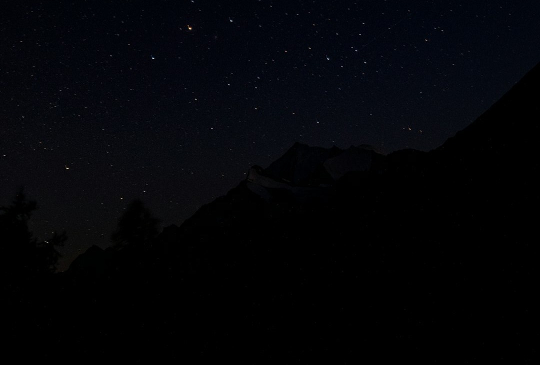 Starry night sky over dark mountain silhouette