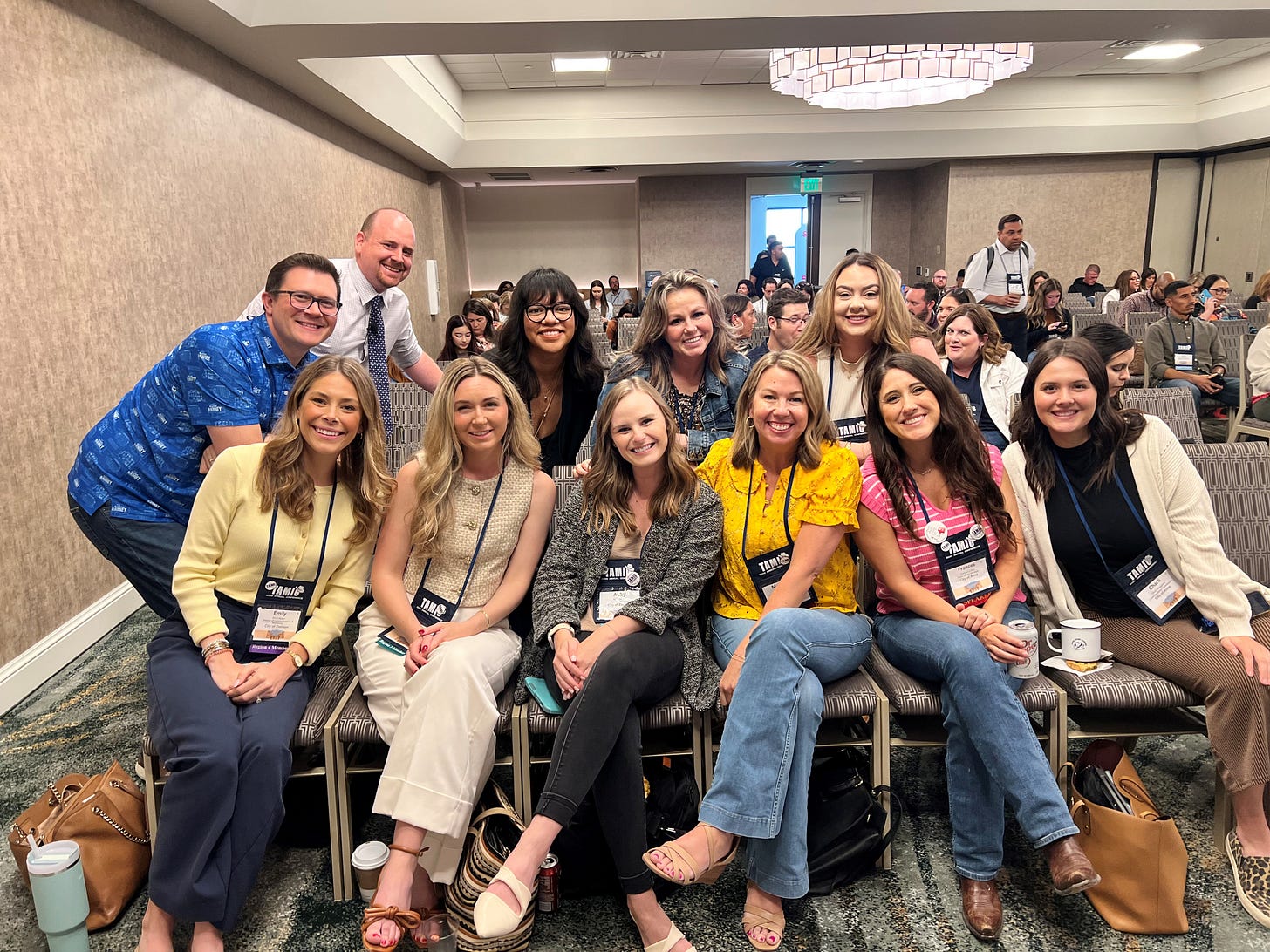 Group photo of local government communicators seated and smiling in the front rows of a conference session at TAMIO 2025. Abby Aldrich, third from the left, joins colleagues in showing support and excitement for an upcoming presentation. A full audience is visible in the background. Group photo of local government communicators seated and smiling in the front rows of a conference session at TAMIO 2025. Abby Aldrich, third from the left, joins colleagues in showing support and excitement for an upcoming presentation. A full audience is visible in the background.