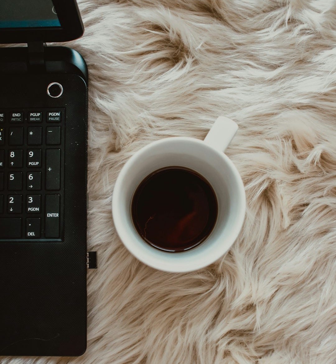 white ceramic mug beside black computer keyboard