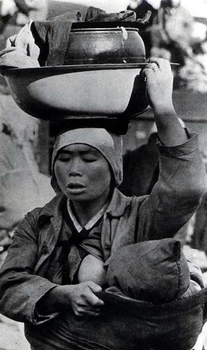 This may contain: a woman carrying two bowls on her head