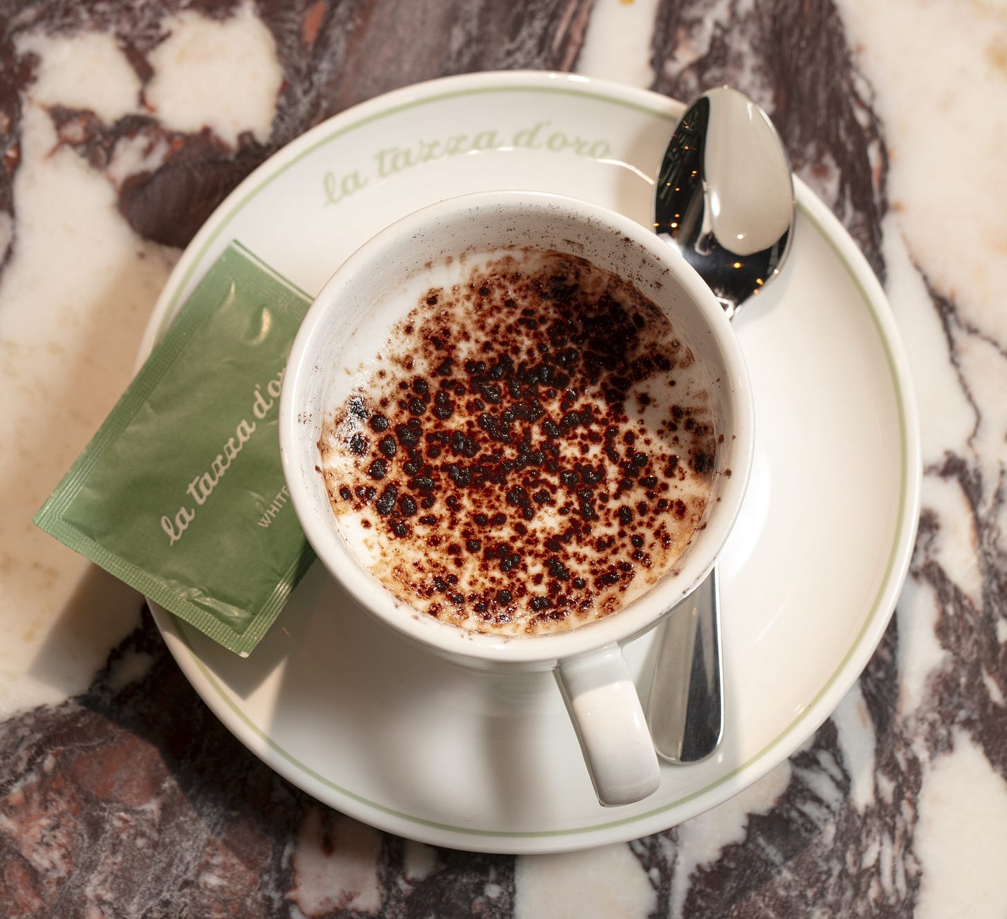 Capolavoro espresso macchiato with cocoa on marble table