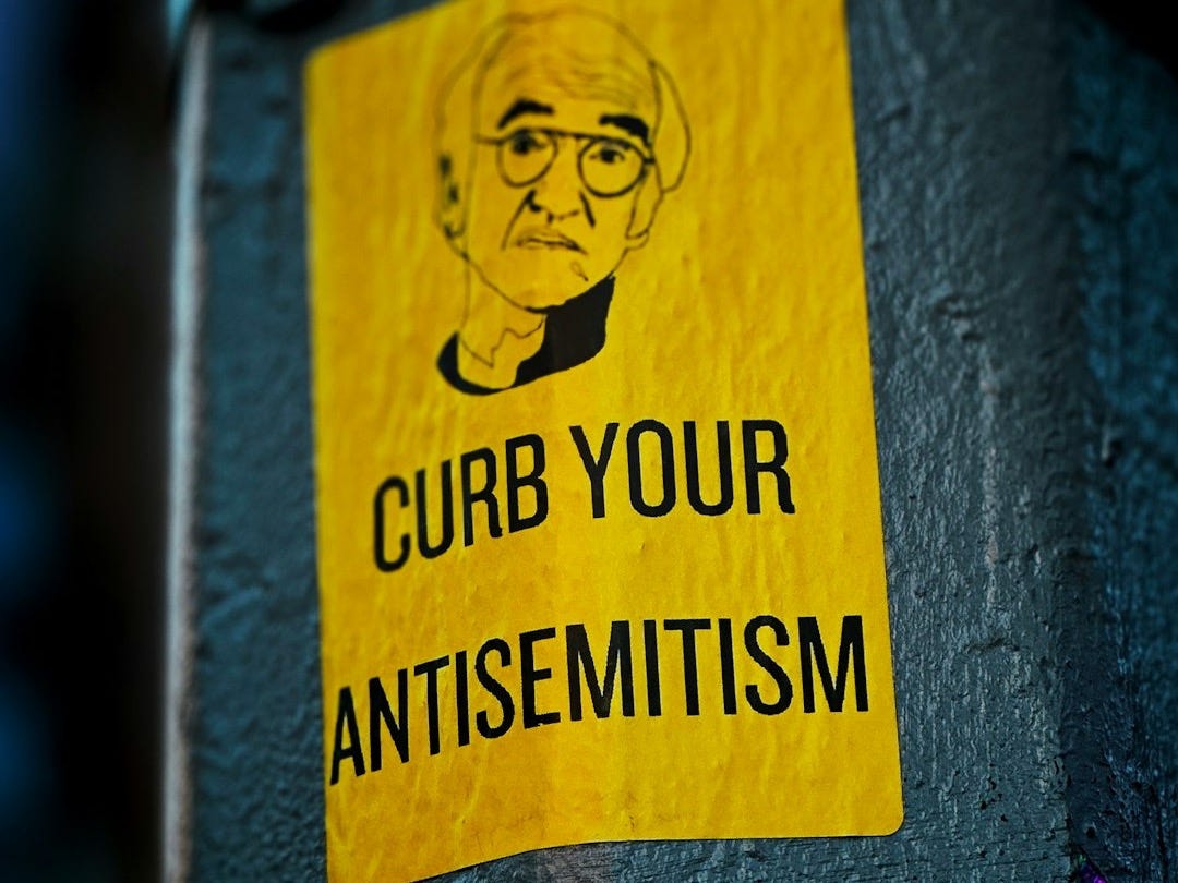 a sticker on the side of a pole that says curb your antisemit