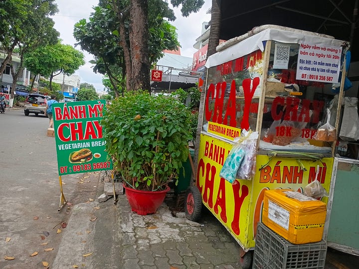 Vietnamese vegetarian sandwich being held in a hand, food cart