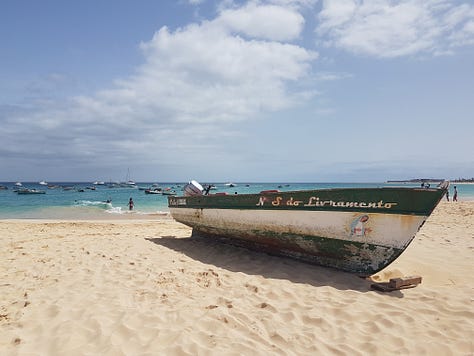 A wooden pier stretching into bright turquoise water, with small waves rolling toward the shore under a clear sky.