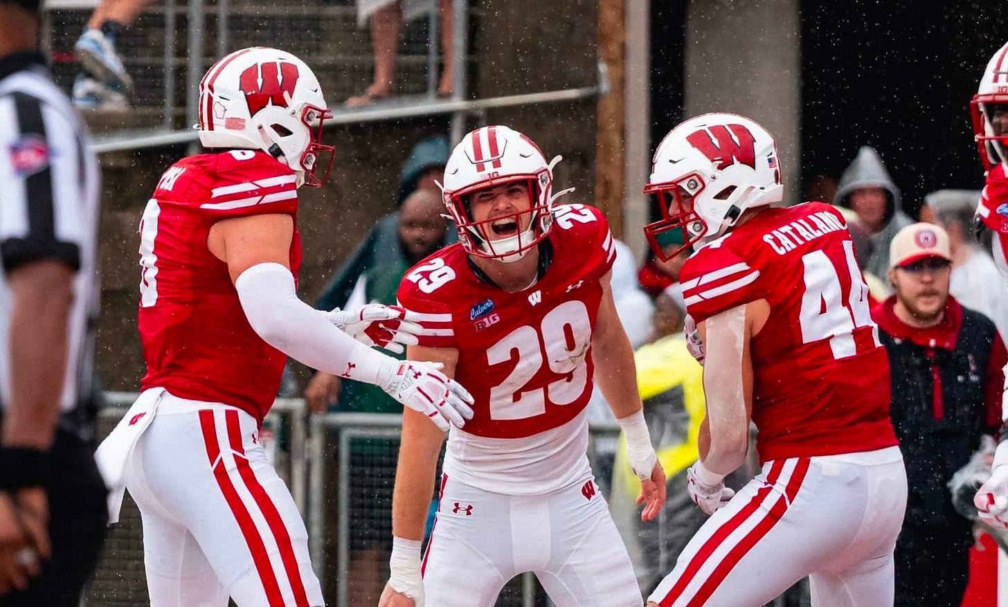 Wisconsin Badgers defenders Cooper Catalano, Mason Posa and Matt Jung celebrate together in the end zone after a touchdown.