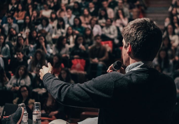 man speaking in front of crowd man speaking in front of crowd