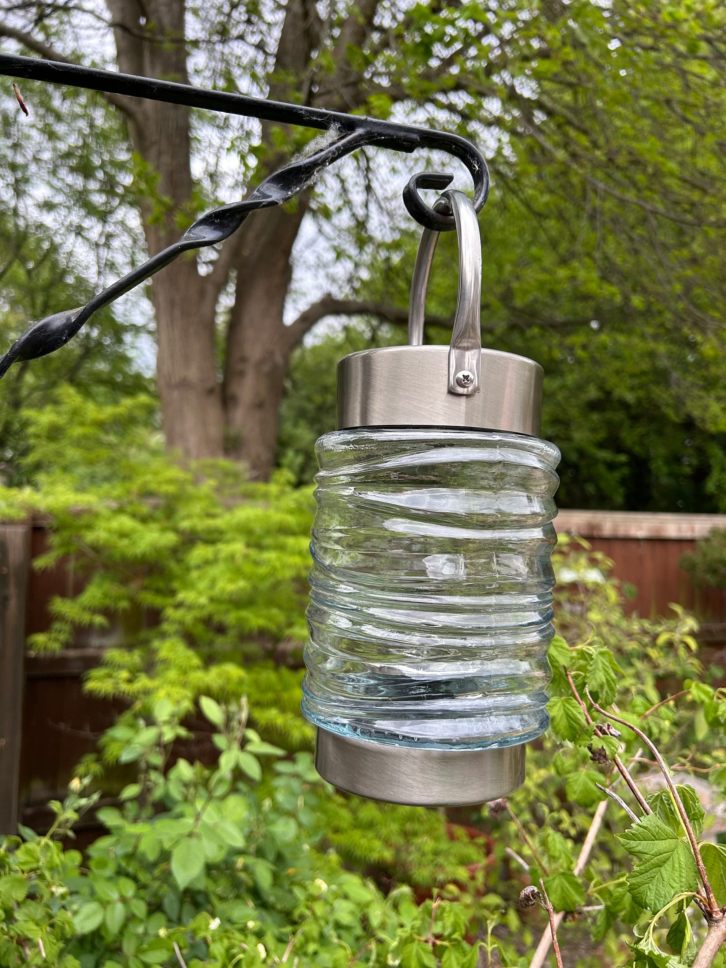A solar powered lantern hanging on a bracket.