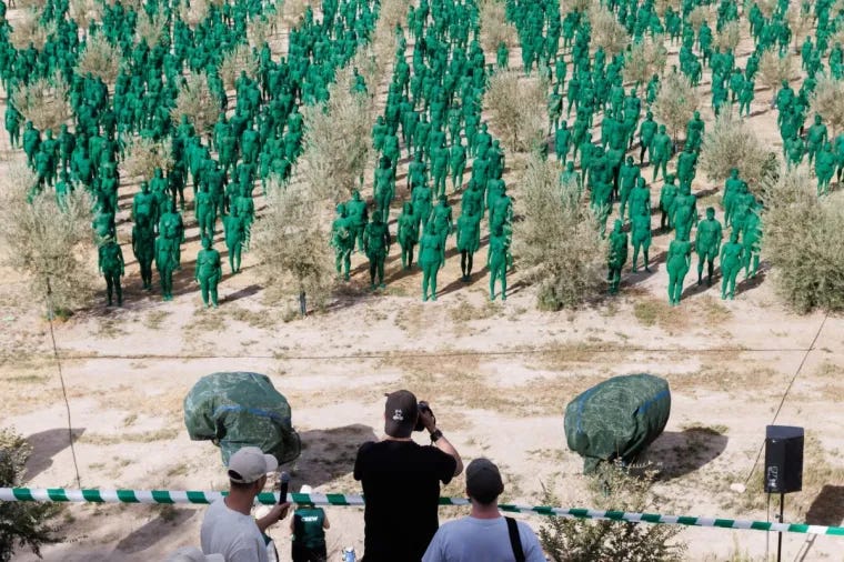 Hundreds of nude volunteers painted green stand among olive trees in a Spanish grove as photographers capture Spencer Tunick’s large-scale installation from a raised platform. Hundreds of nude volunteers painted green stand among olive trees in a Spanish grove as photographers capture Spencer Tunick’s large-scale installation from a raised platform.