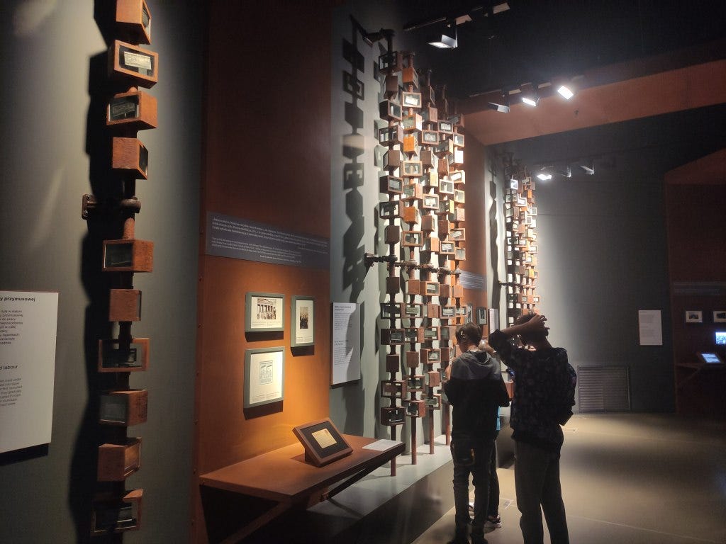 Several pipes from floor to ceiling rotate, showing metal identity plates from those forced into labour