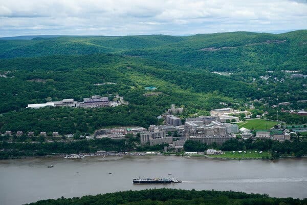 Buildings on a university campus dot a hillside located next to a river. Buildings on a university campus dot a hillside located next to a river.