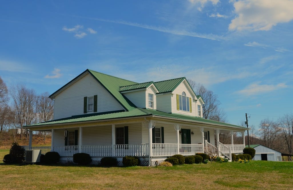a large white house with a green roof a large white house with a green roof