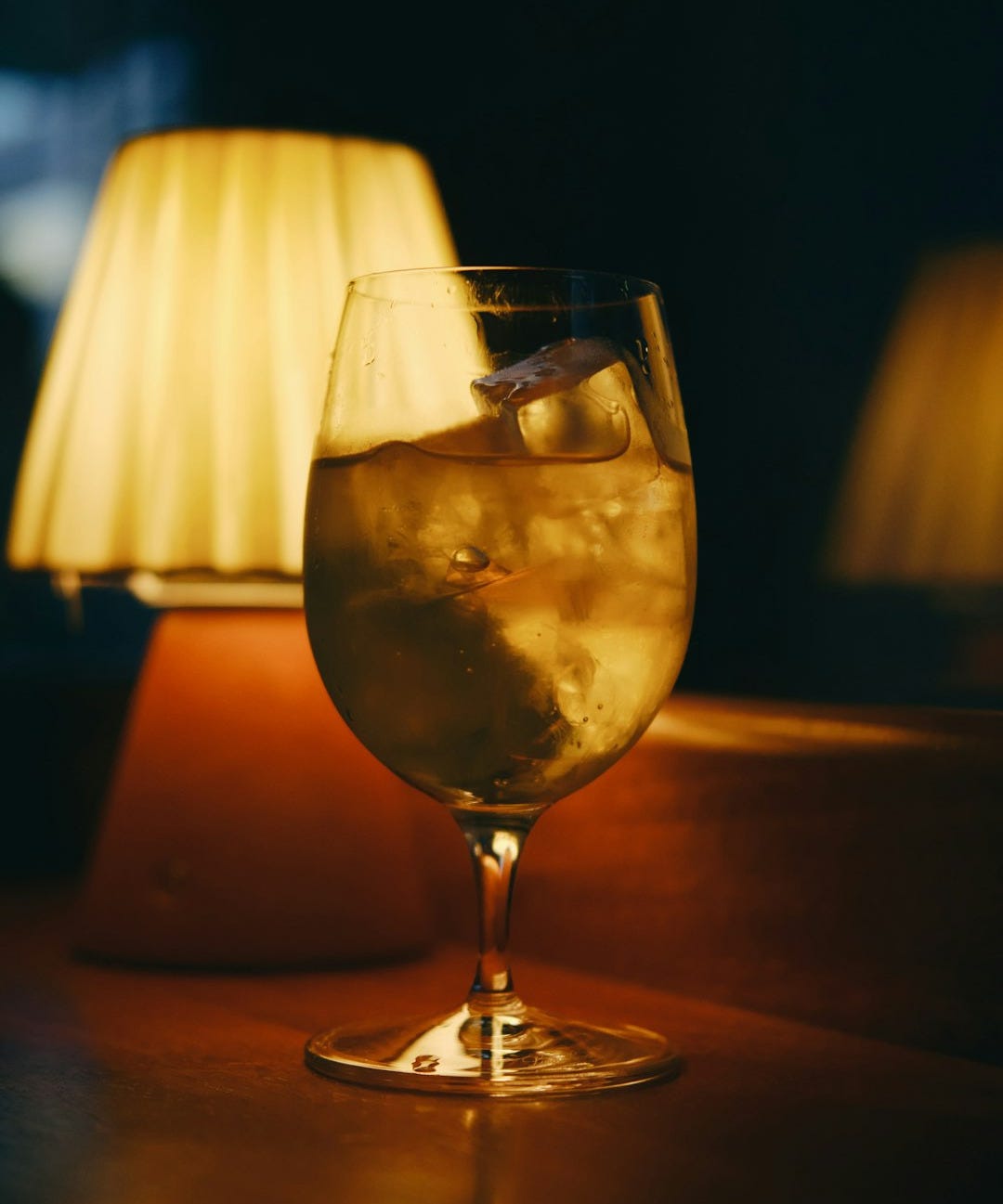 A glass of drink sits beside a lamp.
