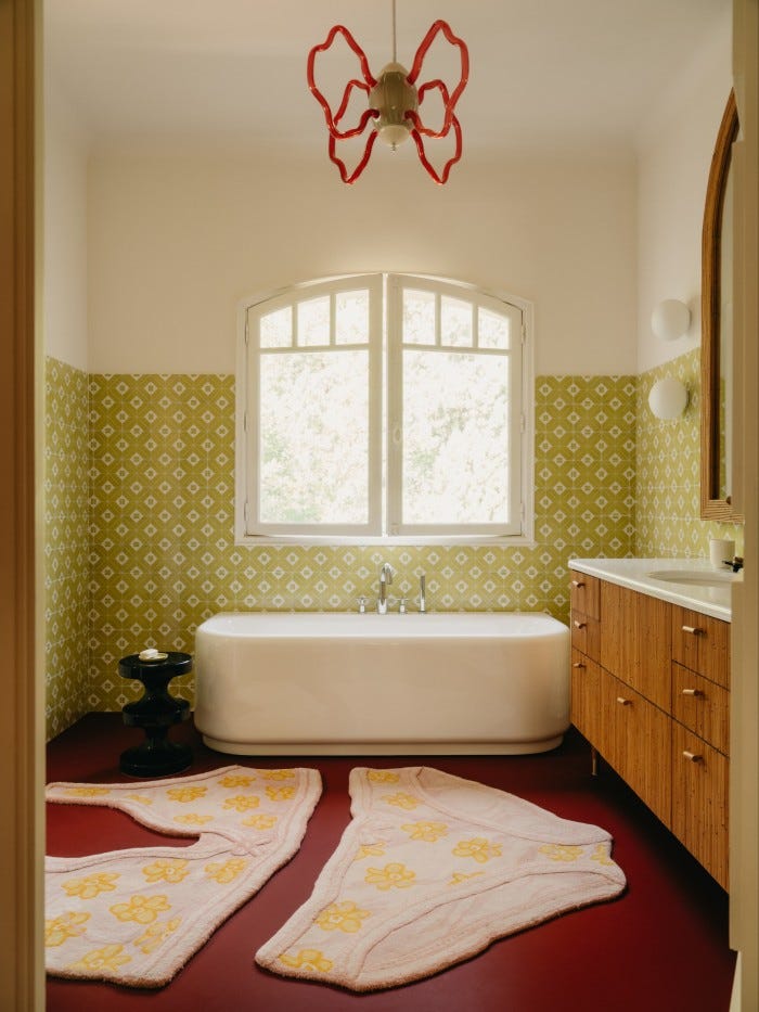 The bathroom, with All Seeing Bra & Briefs rugs by PAM for CC-Tapis, ceiling light by Pierre-Marie, bathtub by Mahdavi for Bisazza and rattan vanity and mirror by Mahdavi.