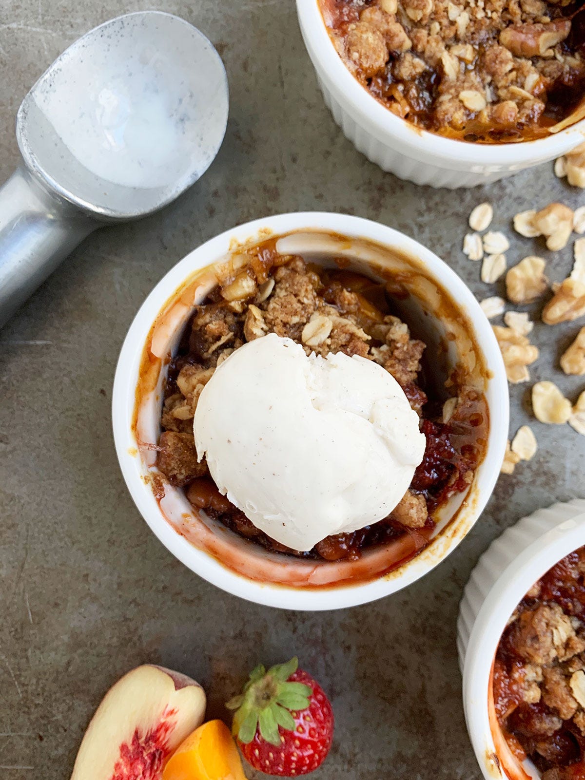 Fruit crisp in individual ramekins with a scoop of ice cream on top.