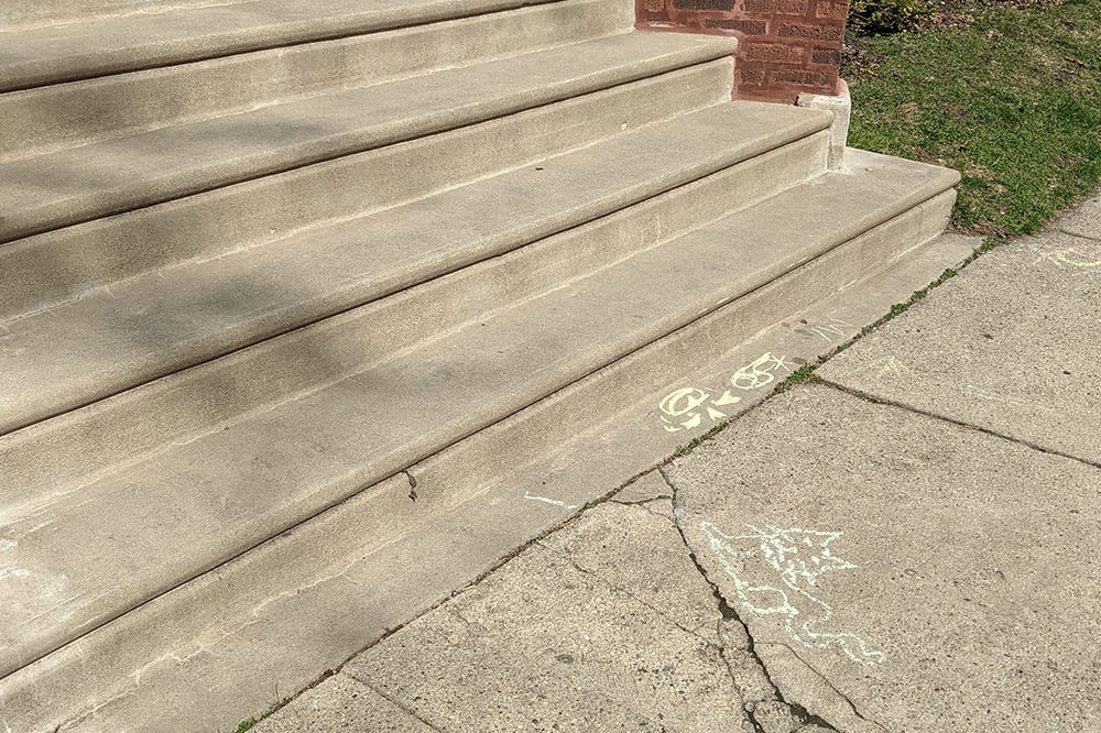 a cute chalk drawing of a cat sit at the end of a cement stoop