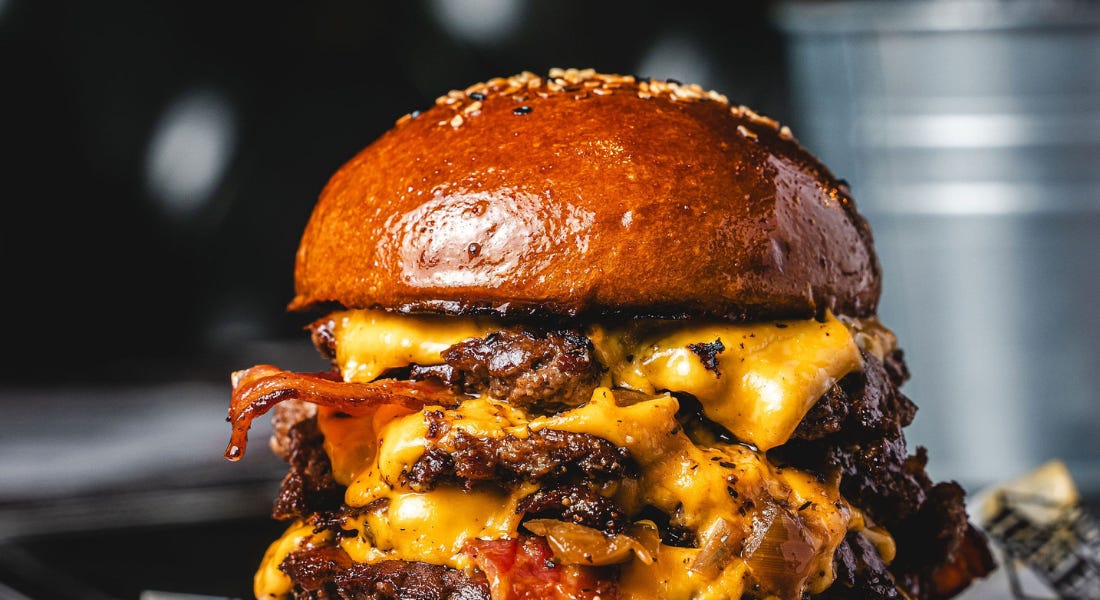 A burger with meat, melted cheese, and a toasted seeded brioche bun A burger with meat, melted cheese, and a toasted seeded brioche bun