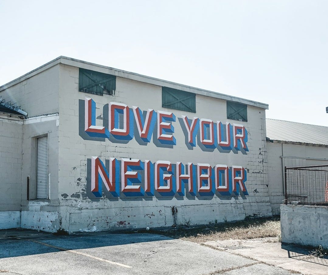 a large sign on the side of a building that says love your neighbor
