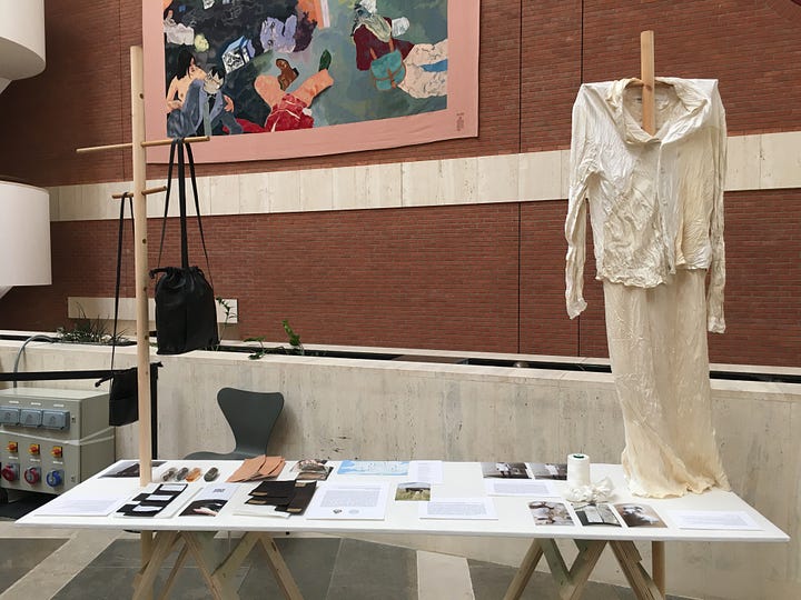 Tables and stick mannequins are layered with garments and research objects for the HERE: An Alternative Route exhibition at the British Library.