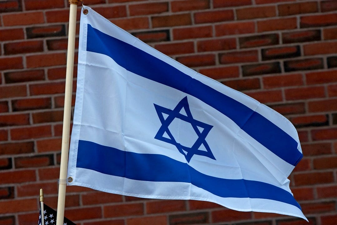A flag flying in front of a brick building A flag flying in front of a brick building