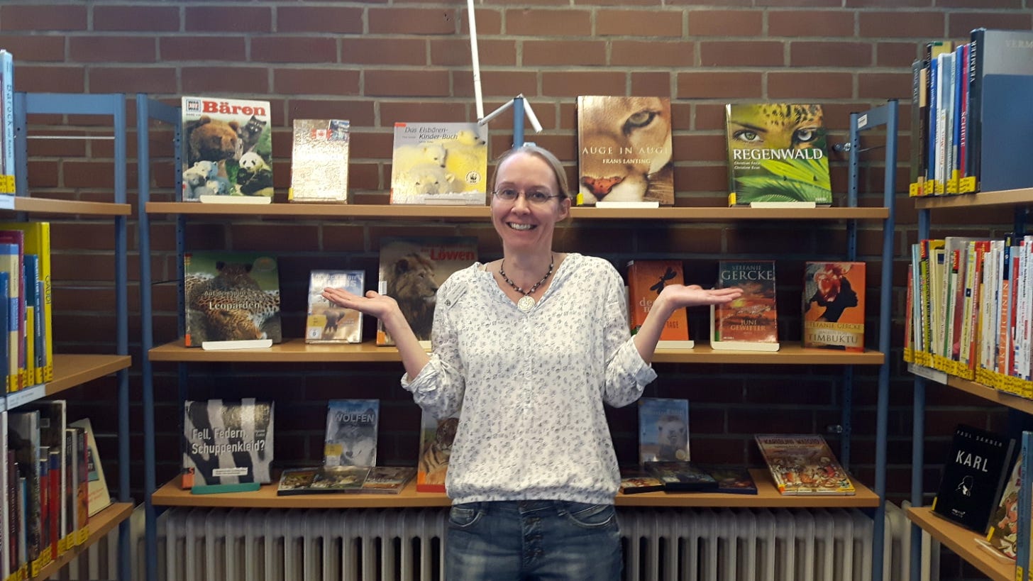 Claudia Kollschen between book shelves in the library