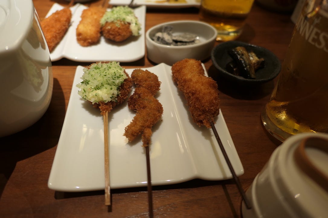 3 deep-fried skewers on a plate. The leftmost skewer has a tartar-like sauce on it. 3 deep-fried skewers on a plate. The leftmost skewer has a tartar-like sauce on it.