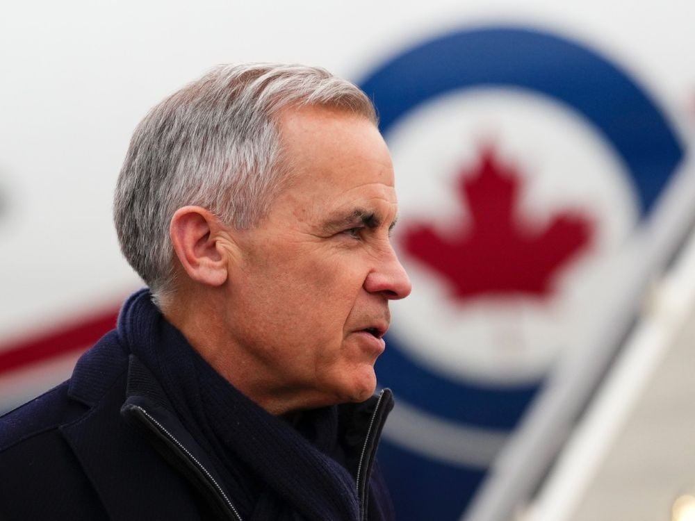 A man in his 60s with gray hair stands before a plane. He wears a black coat and the photo shows his face in profile. In the background, the RCAF logo of a red maple leaf inside a blue circle can be seen on the side of the plane. A man in his 60s with gray hair stands before a plane. He wears a black coat and the photo shows his face in profile. In the background, the RCAF logo of a red maple leaf inside a blue circle can be seen on the side of the plane.