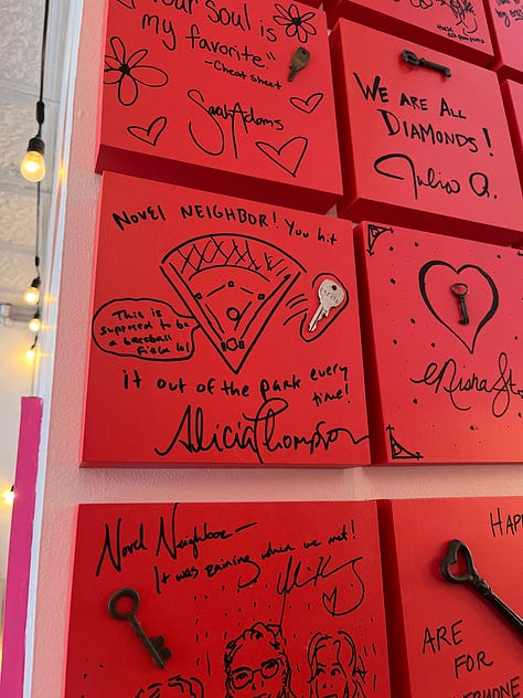 left: exterior of Novel Neighbor; center: Monopoly Board with Novel Neighbor on it; right: red squares on the wall, all signed by authors with keys attached
