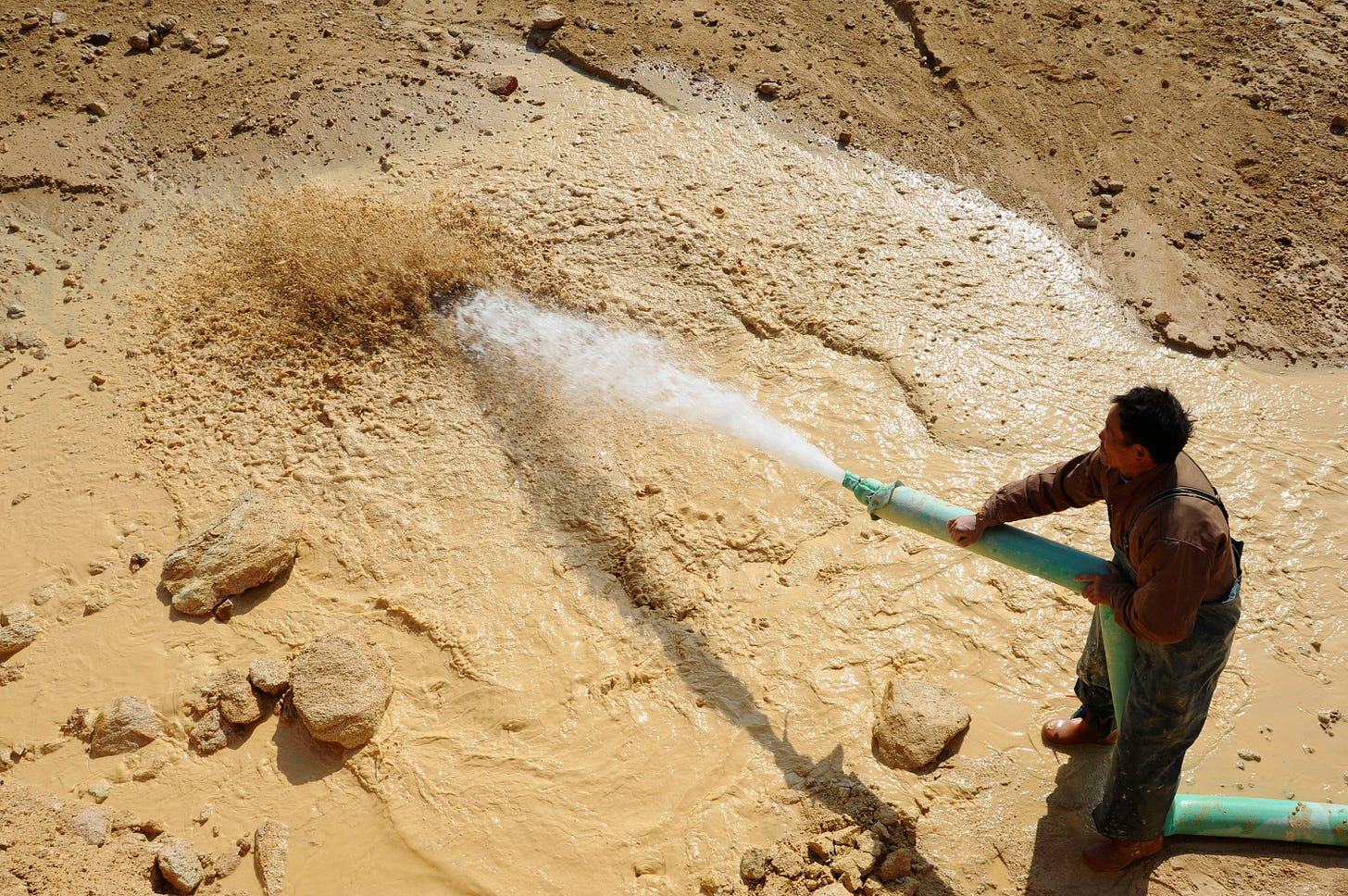 A worker waters the site of a rare earth metals mine at Nancheng county